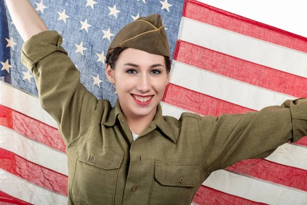 Mladá žena v americké vojenské uniformě, která drží americkou vlajku. Stock Obrázky