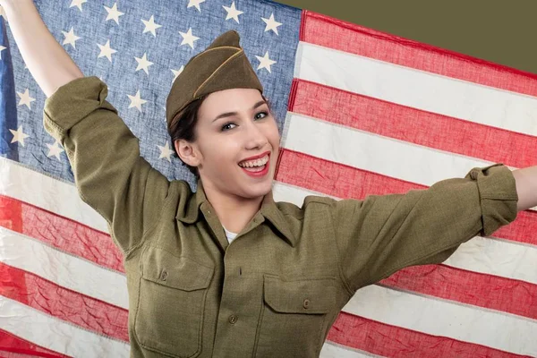 Ung kvinna i USA militär uniform hålla upp en amerikansk flagga. — Stockfoto