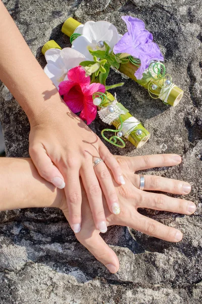 Mãos e anéis no buquê de casamento — Fotografia de Stock