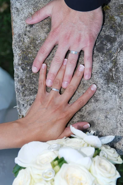 Mãos e anéis no buquê de casamento — Fotografia de Stock