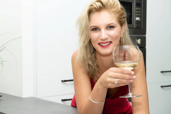 Belle jeune femme blonde avec robe rouge boire du vin blanc — Photo
