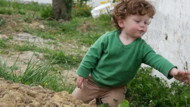jeune garçon avec pull vert jouant en plein air 