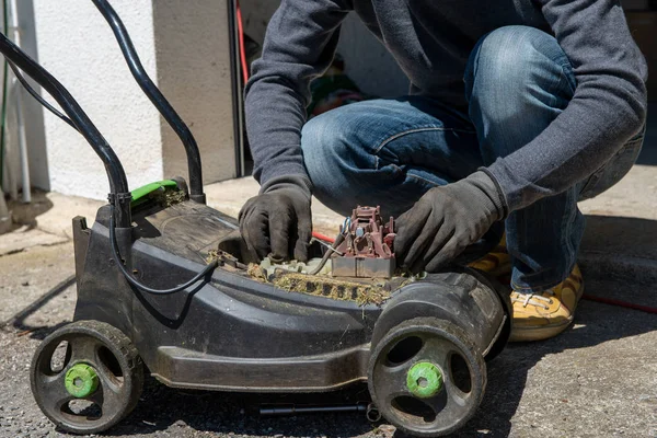 Bir elektrik çim biçme makinesi tamir adam — Stok fotoğraf