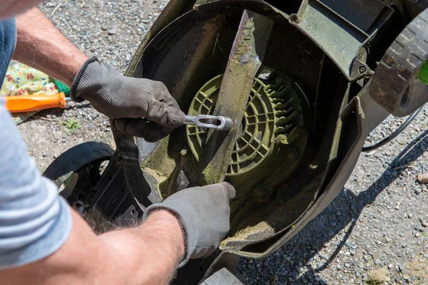 man repairing an electric lawn mower