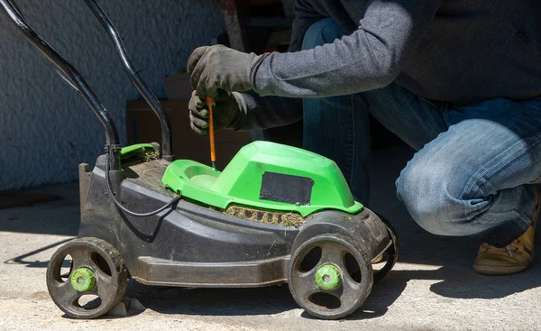 Bir elektrik çim biçme makinesi tamir adam — Stok fotoğraf
