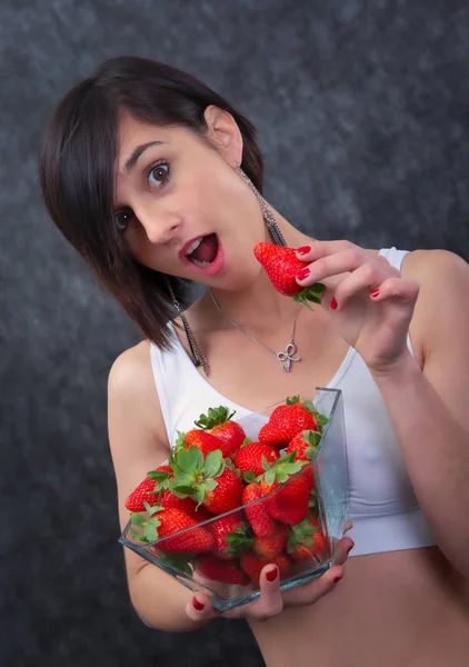 Mooie jonge brunette vrouw die aardbei eet — Stockfoto