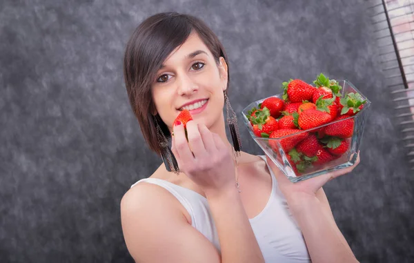 Mooie jonge brunette vrouw die aardbei eet — Stockfoto