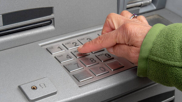 woman enters pin code and withdraws money from  ATM
