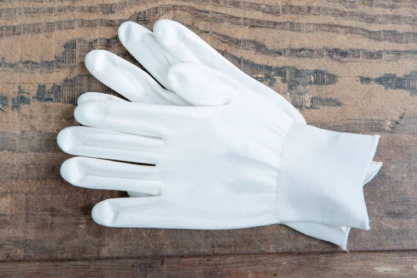 Белые перчатки на деревянном фоне — стоковое фото