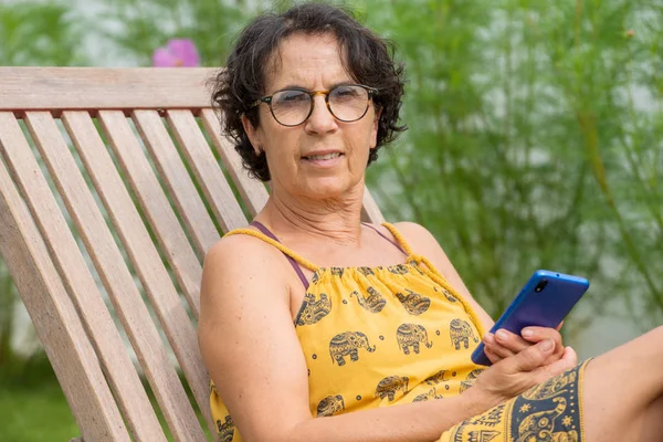 Érett nő pihentető egy kerti gazdaságban és smartphone használata — Stock Fotó