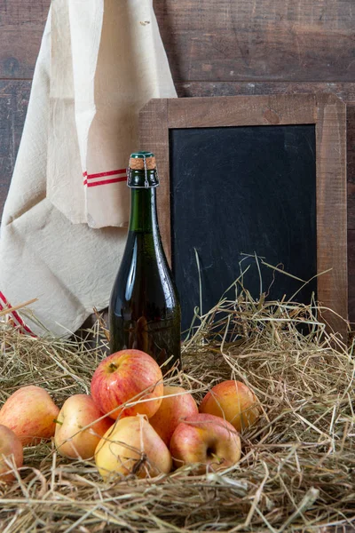 Bottle of cider with apples on the straw — Stock Photo, Image