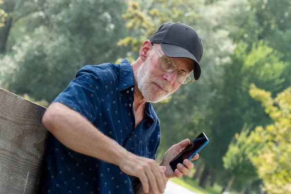 Starszy mężczyzna w Baseball Cap portret za pomocą smartfona — Zdjęcie stockowe