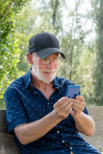 Starszy człowiek w Baseball Cap portret za pomocą smartfona — Zdjęcie stockowe