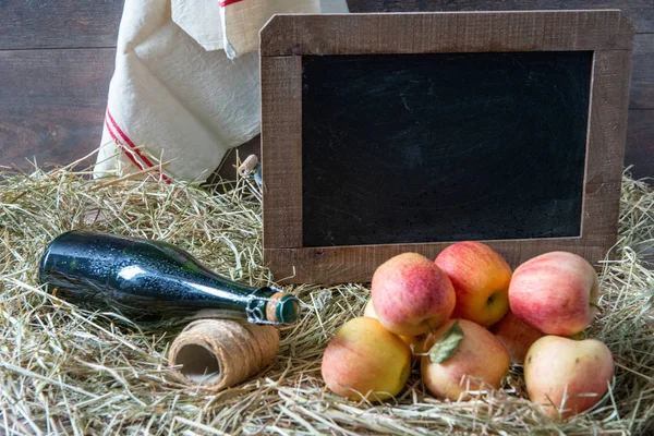 Бутылка сидра с яблоками на соломе и школьная доска — стоковое фото