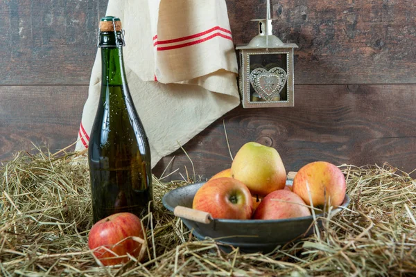Botella de sidra con manzanas en la paja — Foto de Stock