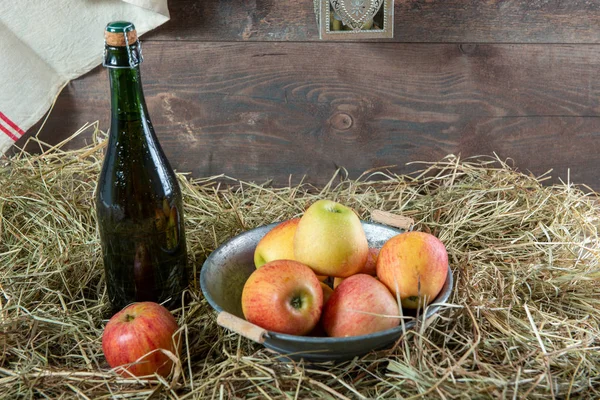 Botella de sidra con manzanas en la paja — Foto de Stock