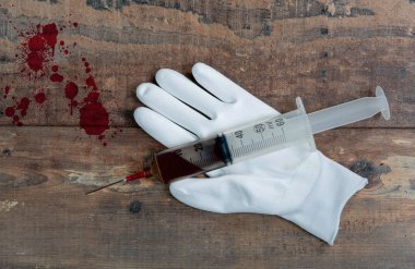 ahşap arka plan üzerinde büyük şırınga ile beyaz eldiven