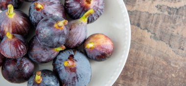 ahşap arka plan üzerinde beyaz bir tabak ta organik incir