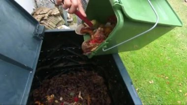 Kadın gübre kutusuna kova dolusu mutfak atıkları boşaltıyor.