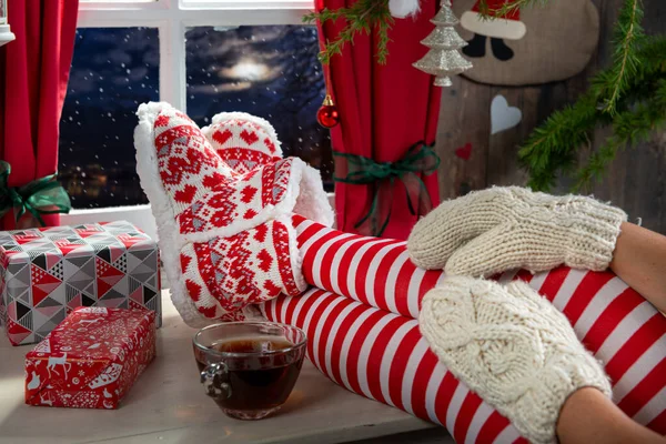 Woman legs with socks on table and background of window, Christm