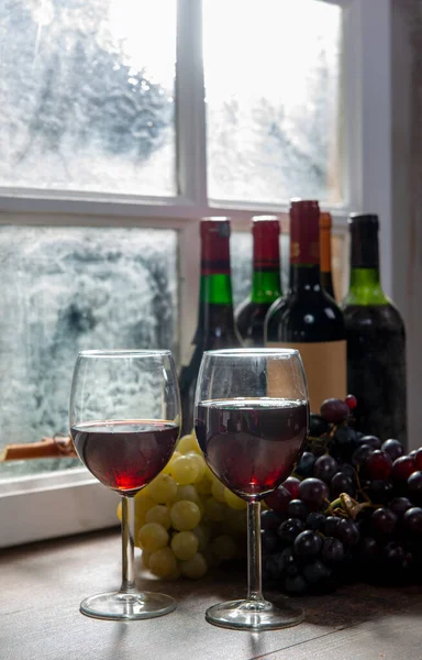 Composition with two wineglasses, grapes and bottles of red wine — Stock Photo, Image