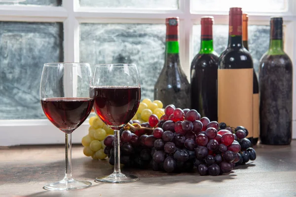 Composition avec deux verres à vin, raisins et bouteilles de vin rouge — Photo