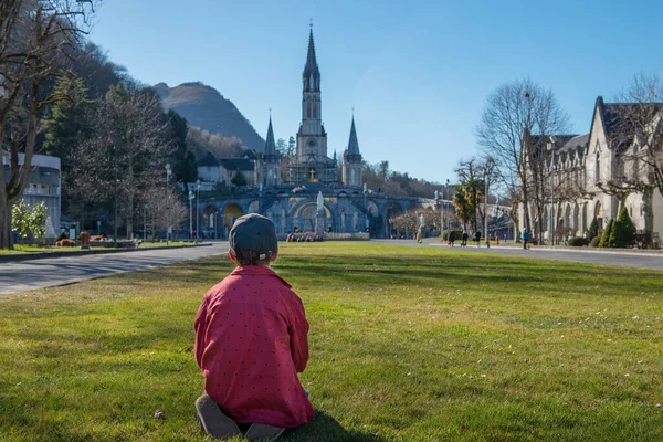 a young boy with the cathedral-sanctuary of Lourdes (France)