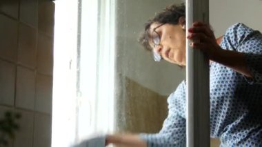 Kadın ev hanımı pencereyi temizliyor.