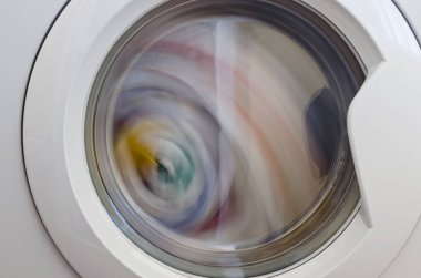 Çamaşır makinesi kapısı ve içinde dönen giysiler.