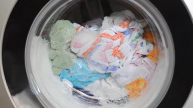 Çamaşır makinesi kapısı ve içinde dönen giysiler.