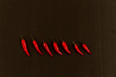 Yedi kırmızı biberler boşaltmak, siyah arka plan, karanlık ile satır.