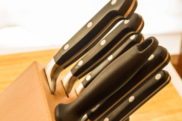 Cooks knives and steel in a line on a chopping board.