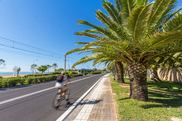 Road by sea in Athens, Greece, with blurred cyclist and tram — Stock Photo, Image