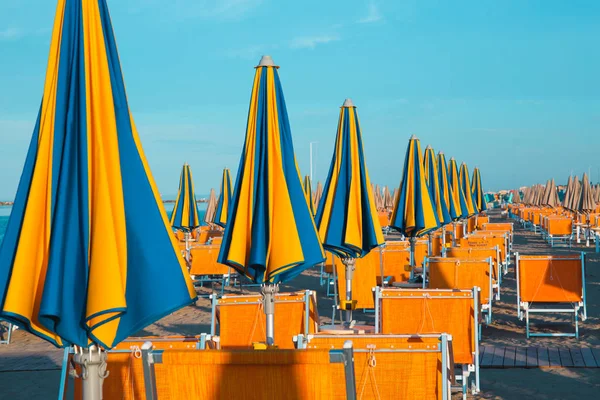 Italian summer on the Adriatic Sea: tyipical italian Riviera Romagnola beach clubs with sunbeds and beach umbrellas with typical vintage colors and look — Stock Photo, Image