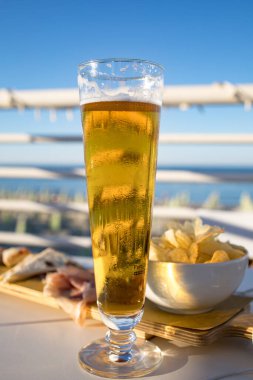 İtalya sahilinde öğleden sonra aperatifi. Büyük bir bardak buz gibi bira ve köpüklü Prosecco şarabı. Mavi gökyüzü arka planı, tam tatil havası..