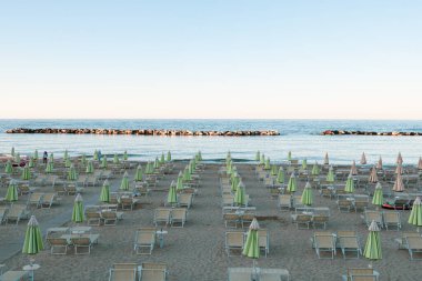 Bellaria Igea Marina, İtalya, 5 Temmuz 2020 / Plaj şemsiyeleri ve güneşli yataklar gün batımından önce. Riviera Romagnola bölgesinde İtalyan Adriyatik kıyıları. Eski tarz görünüş ve his. Deniz manzaralı.