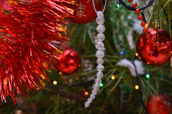 Glace faite de perles sur un sapin de Noël. Fond extérieur de Noël avec branches de sapin, décorations et lumières floues sur le dos . — Photo