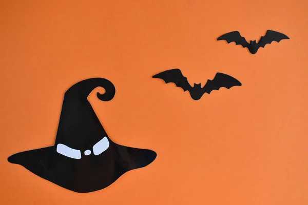 Concept for halloween. Witch hat and bats on an orange background.