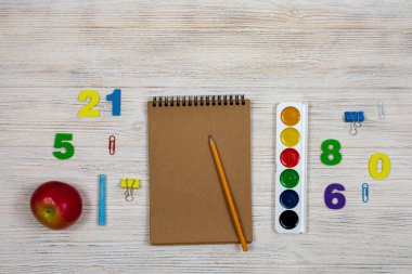 Okul malzemeleri, hafif ahşap arka planda ofis malzemeleri. Düz yerde, üst tarafta. Bir yazıt için yer.