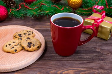 Kırmızı fincanlı çay, kurabiyeli kahve ve ahşap bir masada marshmallowlu Noel süslemeli yeni yıl ağacının arka planına karşı. Sıcaklık ve Yeni Yıl konsepti.