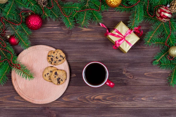 Czerwony kubek herbaty z ciasteczkami na drewnianym stole na tle choinki z zabawkami noworocznymi. Widok z góry. Koncepcja na Nowy Rok, Boże Narodzenie. — Zdjęcie stockowe