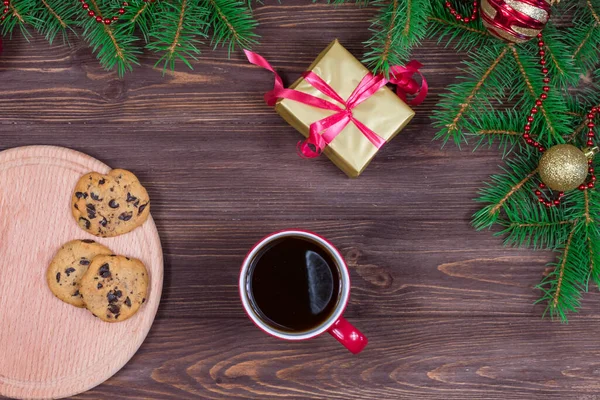 Yeni yıl oyuncaklarıyla bir Noel ağacının arka planına karşı ahşap bir masada duran kurabiyeli kırmızı çay fincanı. Yukarıdan bak. Yeni Yıl, Noel Konsepti.