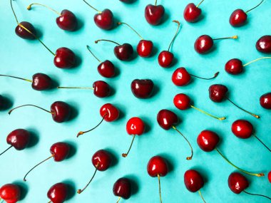 Mavi bir arka planda sulu olgun tatlı kiraz bir sürü. Çevrelerde yer almaktadır. Yukarıdan görüntüle.