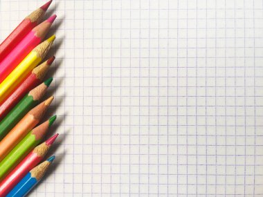 Kafesteki beyaz bir defter yaprağının üzerindeki renkli kalemler. Metin için bir yer var.