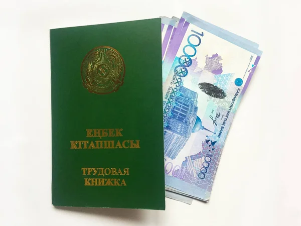Kazakhstan employment record book with several banknotes of 10,000 Kazakhstani tenge invested in it.