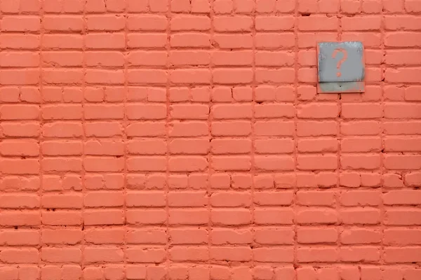 Old orange brick wall with a sign for a house number and other entries