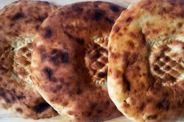 Lezzetli yumuşak ekmek. Yuvarlak kızarmış tortilla lar tahta bir masanın üzerine uzanır. Yakın çekim, üst görünüm.