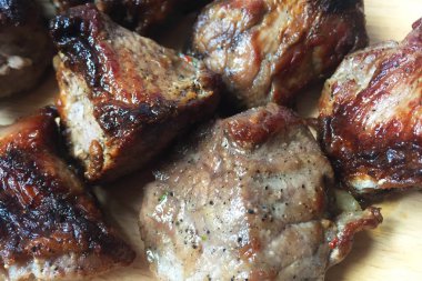 Lezzetli sulu ızgara et. Büyük parçalar ahşap bir masanın üzerinde yatıyor. Çeşitli kavurma eti. Yakın çekim, üst görünüm.