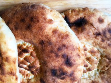 Lezzetli yumuşak ekmek. Yuvarlak kızarmış tortilla lar tahta bir masanın üzerine uzanır. Yakın çekim, üst görünüm.