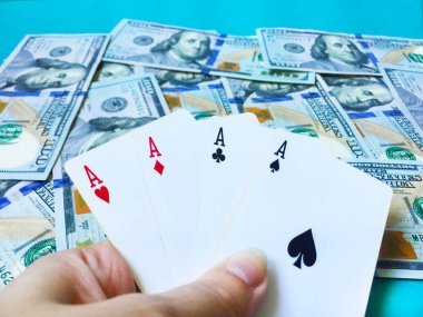 Yüz dolarlık banknotların arka planına karşı farklı takım elbiseli eski oyun kartlarının dört as kazanan bir poker eli. Üst görünüm, yakın çekim.